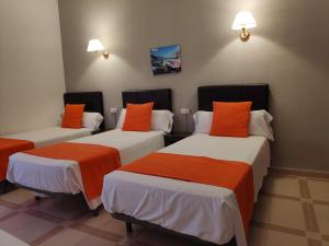 drie bedden in een kamer met oranje en wit bij Hotel Perú by Bossh! Hotels in Trujillo +87 foto's