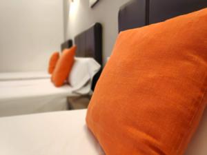 een oranje kussen bovenop een bed bij Hotel Perú by Bossh! Hotels in Trujillo