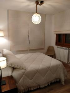um quarto com uma grande cama branca e um lustre em Apartamentos La Glera Biescas em Biescas