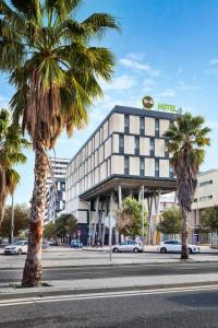 a hotel with palm trees in front of a street at B&B HOTEL Barcelona Mataro in Mataró