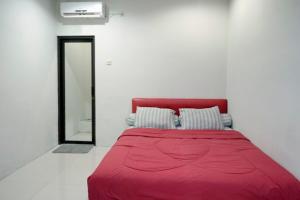 a red bed in a white room with a mirror at D'Paragon Bukit Sari in Semarang
