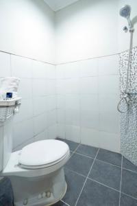 La salle de bains blanche est pourvue d'une douche et de toilettes. dans l'établissement D'Paragon Bukit Sari, à Semarang