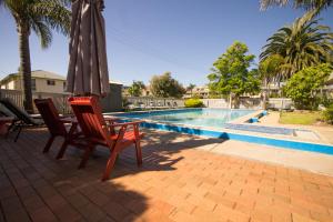 a patio area with a pool and chairs at Kalindo Merimbula in Merimbula