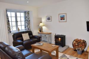 a living room with a leather couch and a wood stove at Osprey Cottage, Port o Tay in Pitlochry