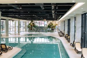 a swimming pool in a building with chairs around it at Hotel Perla in Baile Unu Mai +19 photos