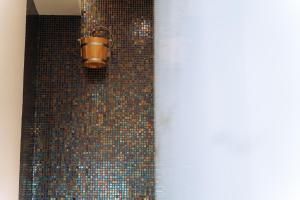 a shower with a bucket on a mosaic wall at Hotel Perla in Baile Unu Mai