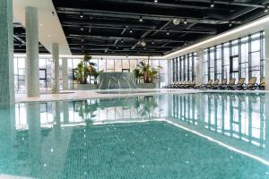 a swimming pool with chairs in a building at Hotel Perla in Baile Unu Mai