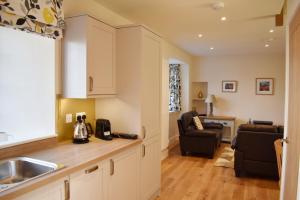 a kitchen with a sink and a living room at Osprey Cottage, Port o Tay in Pitlochry