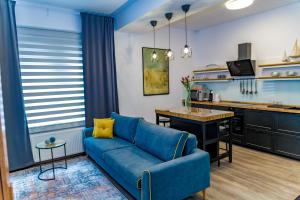 a living room with a blue couch and a kitchen at Villa Casafina Serviced Apartments in Mangalia