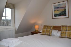 a bedroom with a white bed and a window at Osprey Cottage, Port o Tay in Pitlochry