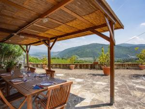 a wooden table and chairs under a wooden pergola at Villa Villa Monteloro by Interhome in Ellera