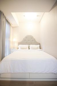 ein weißes Schlafzimmer mit einem großen Bett mit weißer Bettwäsche in der Unterkunft Classica by Kozystay - Kuningan in Jakarta