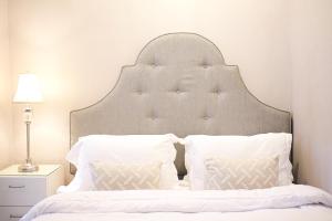ein weißes Bett mit großem Kopfteil und zwei Kissen in der Unterkunft Classica by Kozystay - Kuningan in Jakarta