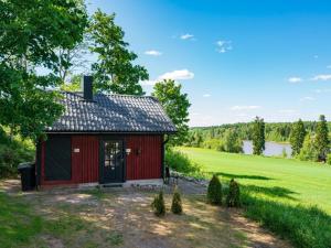 ein roter Schuppen auf einem Feld neben einem See in der Unterkunft Holiday Home Pikkupehtoori by Interhome in Hirsjärvi