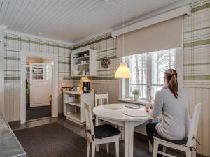 una mujer sentada en una mesa en una cocina en Holiday Home Pikkupehtoori by Interhome, en Hirsjärvi