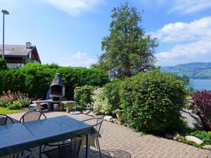 eine Terrasse mit einem Tisch, einem Grill und Büschen in der Unterkunft Holiday Home Chalet Marbach by Interhome in Faulensee