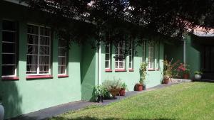 een groen gebouw met ramen en planten in een tuin bij Sugarbush & Burgundy in Zeerust