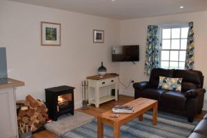 a living room with a couch and a fireplace at Heron Cottage, Port o Tay in Pitlochry