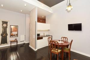 uma cozinha e sala de jantar com uma mesa e um relógio em Apartament Patisserie by Good Time em Lódź