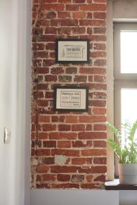 a brick wall with two framed pictures on it at Apartament Patisserie by Good Time in Łódź