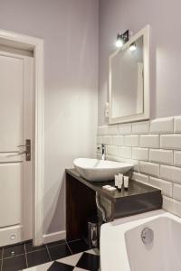 a bathroom with a tub and a sink and a mirror at Apartament Patisserie by Good Time in Łódź