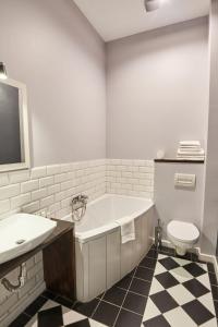 a bathroom with a tub and a toilet and a sink at Apartament Patisserie by Good Time in Łódź