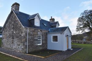 una casa con un cobertizo a un lado en Heron Cottage, Port o Tay en Pitlochry