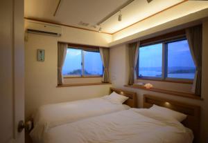 two beds in a room with two windows at Kasane / The Family Villa in Ishigaki Island