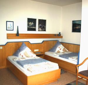 two twin beds in a room with a chair at Pension am Walde in Beerfelden