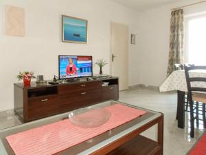 a living room with a tv and a table at Holiday Home Bernardi by Interhome in Lumbarda