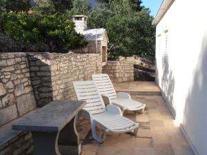 two white chairs and a table on a patio at Holiday Home Bernardi by Interhome in Lumbarda +14 photos