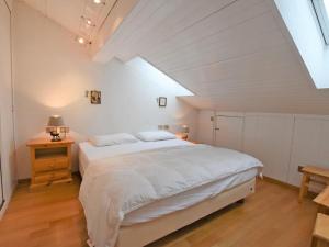 a bedroom with a white bed and a wooden floor at Apartment Apt 41 by Interhome in Alba di Canazei