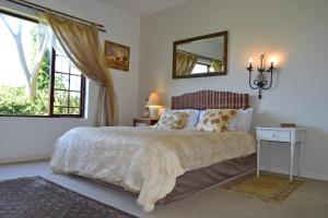 1 dormitorio con cama con espejo y ventana en Sea Valley Villa, en Port Alfred