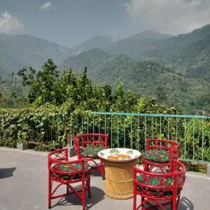 three red chairs and a table with a view of mountains at ROSASTAYS Jeolikote in Nainital