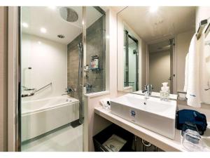 a bathroom with a sink and a shower and a tub at Daiwa Roynet Hotel Kumamoto in Kumamoto