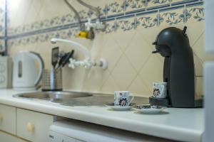 a coffee maker and two cups on a kitchen counter at Romantic Apartment + Tejo River View in Lisbon