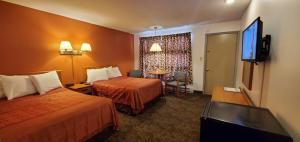 Habitación de hotel con 2 camas y TV de pantalla plana. en Pinebrook Motel, en Lake George
