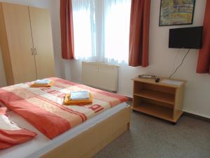 a bedroom with a bed and a table and a television at Pension "Zur Katze" in Gelenau