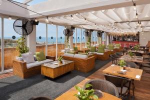 ein Restaurant mit Sofas, Tischen und Fenstern in der Unterkunft Alexander Hotel in Tel Aviv