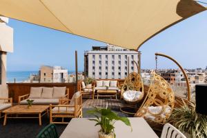 a patio area with chairs, tables and umbrellas at Alexander Hotel in Tel Aviv