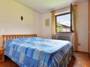 een slaapkamer met een bed met een blauw dekbed en een raam bij Apartment Cesa Palua by Interhome in Alba di Canazei