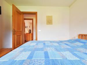 a bedroom with a bed with a blue comforter at Apartment Cesa Palua by Interhome in Alba di Canazei