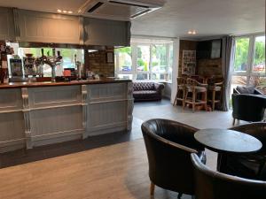 a restaurant with a bar with leather chairs and tables at Hunters Meet in Bishops Stortford