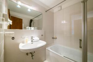a white bathroom with a sink and a shower at Haus Roland in Helgoland