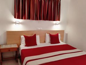 una camera da letto con un letto con cuscini rossi e bianchi di Apartamentos Calma a Playa del Ingles