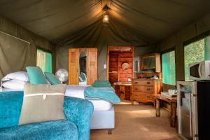 a bedroom with a bed and a couch in a tent at Fernhill Tented Treehouses in Rheenendal