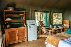 una habitación con nevera y una mesa en una tienda de campaña en Fernhill Tented Treehouses en Rheenendal