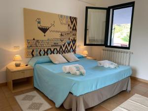 1 dormitorio con 1 cama azul y 2 almohadas en Agriturismo Lu Branu en Arzachena