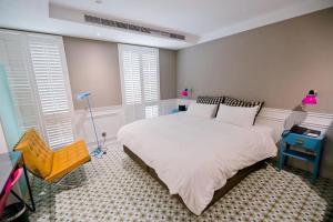 a bedroom with a white bed and a yellow chair at 朵兒dor韓國汗蒸幕 동대문점 商務旅店 in Taipei