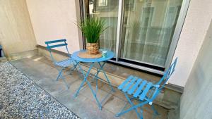 duas cadeiras azuis e uma mesa com um vaso de plantas em Cosy Break Jardins des plantes em Le Mans